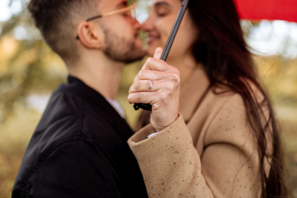 couple s'embrassant sous la pluie avec parapluie rouge, couleurs chaudes et douces