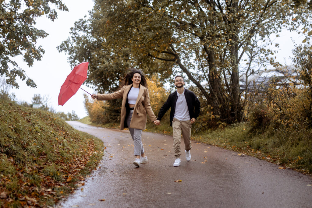 couple qui court sous la pluie avec parapluie rouge