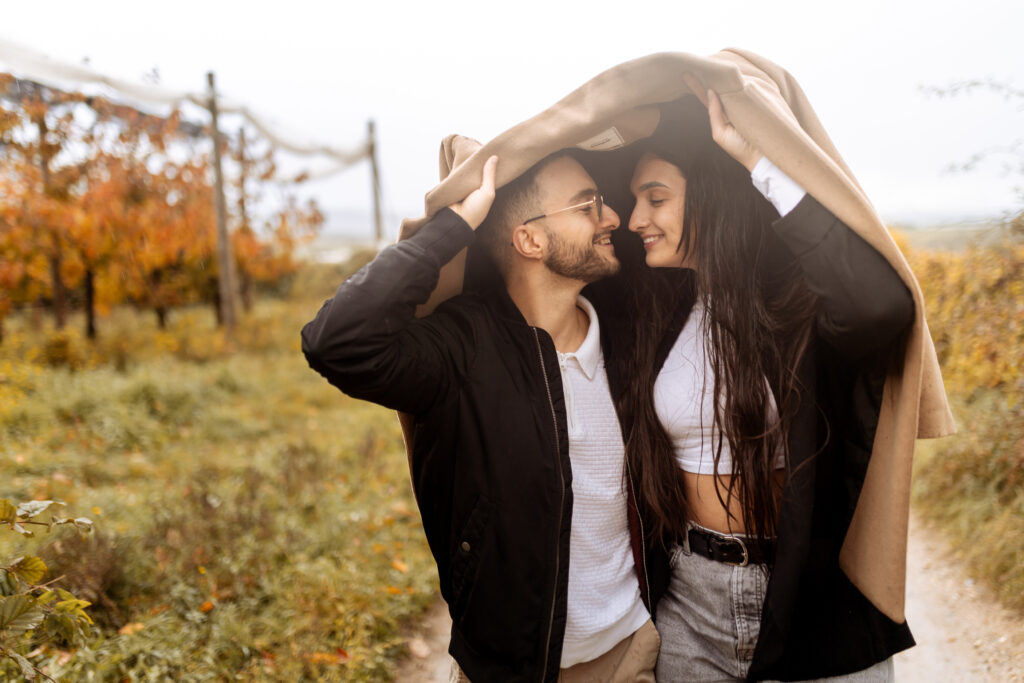 couple qui s'abrite sous un manteau, sous la pluie - couleurs douces et chaudes